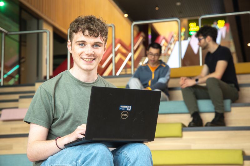 student on laptop on one elmwood staircase